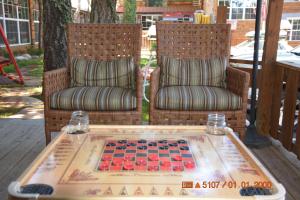 two chairs and a chessboard on a table on a porch at Sitzmark Chalet Inn in Ruidoso