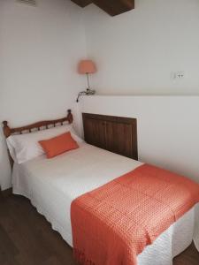 1 dormitorio con 1 cama y 1 lámpara en la pared en Casa Rural El Enebro, en Navamorcuende