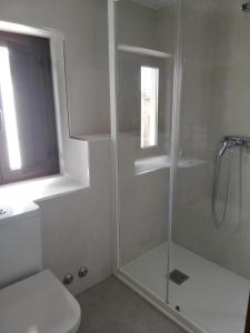 a white bathroom with a shower and a toilet at Casa Rural El Enebro in Navamorcuende