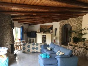 una sala de estar con sofás azules y una pared de piedra. en Villa Federica, en Villa Targia
