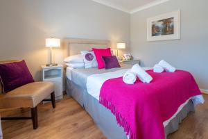 ロスレアにあるCoral Gables Guesthouse & Campsiteのベッドルーム1室(ピンクのシーツと椅子が備わるベッド2台付)
