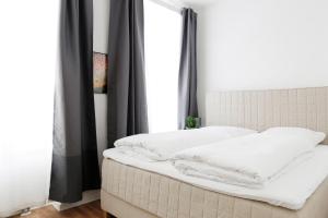 Bett mit weißen Kissen in einem Zimmer mit Fenster in der Unterkunft Be in Berlin Apartments in Prenzlauer Berg in Berlin