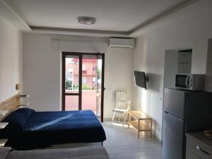 a room with a bed and a kitchen with a refrigerator at B&B Le Meduse in Fiumicino