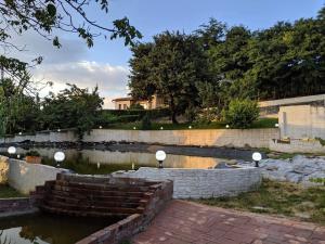 un jardin avec un mur en pierre et un étang dans l'établissement Camping Robinson Country Club Oradea, à Oradea