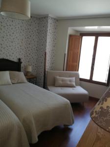 um quarto com uma cama, uma cadeira e uma janela em Hostal El Resbalon em Cervera de Pisuerga