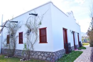 a white house with red windows and a sidewalk at Balcones de San Carlos - casa Balcones in Cafayate