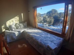 een slaapkamer met een bed en een groot raam bij Lago Mistico in Villa Pehuenia