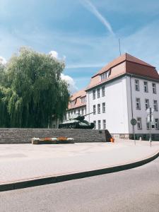 biały budynek z czerwonym dachem na ulicy w obiekcie Apartament Przy Deptaku w Drawsku Pomorskim +15 zdjęć
