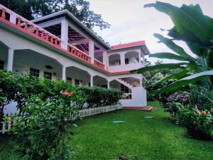 a large white building with a green yard at Polish Princess Guest House in Port Antonio