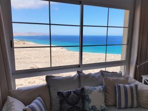 a couch in front of a window with a view of the beach at Casa Storm in Costa Calma