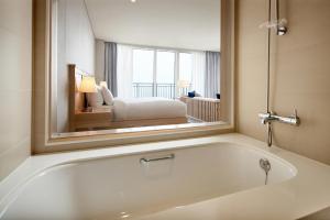 a bathroom with a bath tub with a mirror at Lotte Resort Sokcho in Sokcho