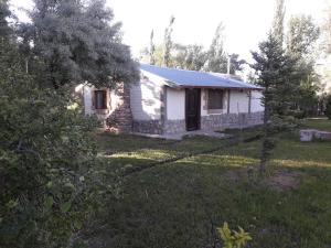 uma pequena casa branca num quintal com árvores em Chalecito Campestre Centrico em Malargüe