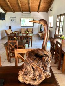 Habitación con mesas, sillas y una escultura de madera. en Posada Che Teindy en Colonia Carlos Pellegrini