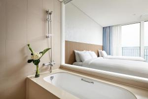 a bathroom with a bath tub and a large mirror at Lotte Resort Sokcho in Sokcho