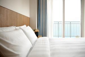 a bed with white pillows in a room with a window at Lotte Resort Sokcho in Sokcho