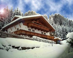 a building covered in snow with trees in the background at Alberta's Ferienhaus in Heinfels