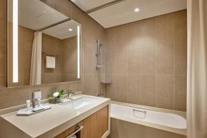 a bathroom with a sink and a tub and a mirror at Lotte Resort Sokcho in Sokcho