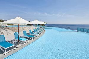 a swimming pool with chairs and umbrellas and the ocean at Lotte Resort Sokcho in Sokcho