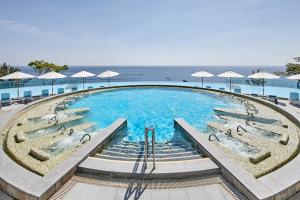 a large swimming pool with umbrellas and the ocean at Lotte Resort Sokcho in Sokcho