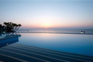a swimming pool with a sunset in the background at Lotte Resort Sokcho in Sokcho