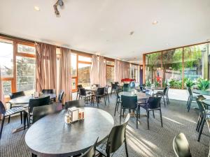 a restaurant with tables and chairs and windows at Snowy Valley Jindabyne in Jindabyne