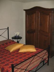 a bed with two pillows and a wooden cabinet at La Miseria in Ovada