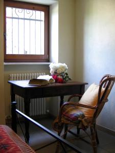 a table with a book and flowers and a chair at La Miseria in Ovada