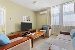 Launceston Central Apartment Hotel Official في لونسيستون: غرفة معيشة مع أريكة وتلفزيون