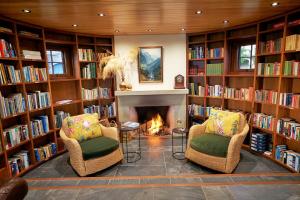 une bibliothèque avec deux chaises et une cheminée dans l'établissement Cabot Lodge - Fiordland National Park, à Manapouri