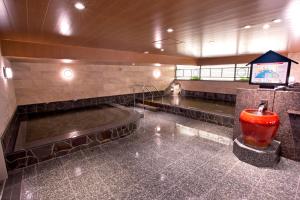 a bathroom with a tub and a tv in a building at Natural Hot Spring Yaoji Hakata Hotel in Fukuoka