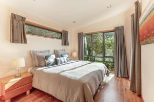 a bedroom with a bed and a large window at Moeraki with private walkway to Onetangi Beach by Waiheke Unlimited in Onetangi