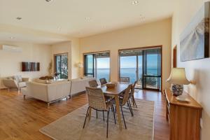 a living room with a table and chairs and a couch at Moeraki with private walkway to Onetangi Beach by Waiheke Unlimited in Onetangi