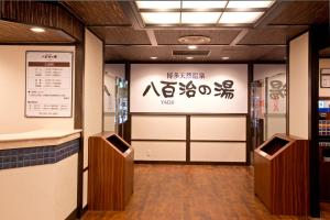 un vestíbulo con puertas y una señal en un edificio en Natural Hot Spring Yaoji Hakata Hotel en Fukuoka