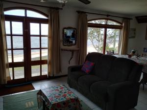 ein Wohnzimmer mit einem Sofa und zwei großen Fenstern in der Unterkunft Lago Merin in Lago Merin