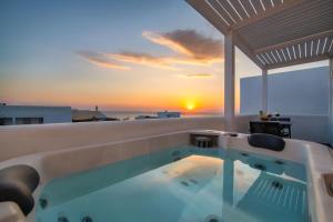 una vasca idromassaggio sul tetto di una casa con il tramonto di Elea Hub a Oia