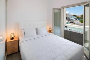 um quarto com uma grande cama branca e uma varanda em Elea Hub em Oia