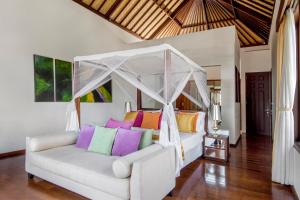 ein Schlafzimmer mit einem weißen Bett und bunten Kissen in der Unterkunft Villa Amanie - Private Villa with Infinity pool, Stunning Views and Cook in Jimbaran + 20 Fotos