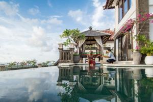 ein Paar, das neben einem Pool in einer Villa sitzt in der Unterkunft Villa Amanie - Private Villa with Infinity pool, Stunning Views and Cook in Jimbaran