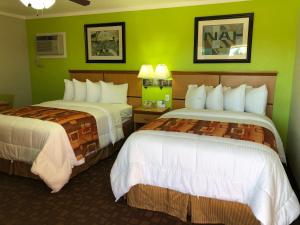 Copa Motel في Kingman: سريرين في غرفة فندق بجدران خضراء