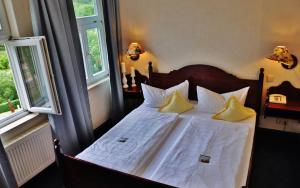 Schlafzimmer mit einem Bett mit weißer Bettwäsche und gelben Kissen in der Unterkunft Flair-Hotel Waldfrieden in Meuselbach-Schwarzmühle