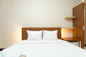 a bed with white sheets and a wooden headboard at Modern Studio Apartment at Cinere Resort By Travelio in Depok +7 photos