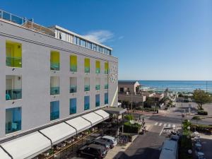 a hotel on the beach with the ocean in the background at Hotel Adelphi in Riccione
