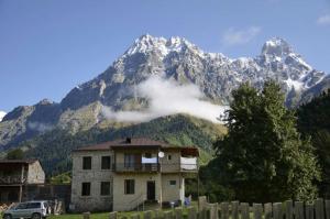 a house in front of a mountain with a fence at Peak Mazeri Guest House in Mazeri