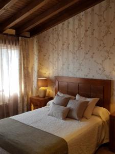 ein Schlafzimmer mit einem großen Bett mit weißer Bettwäsche in der Unterkunft CASA RURAL VERSOS in San Martín del Castañar