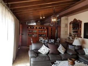 a living room with a leather couch and a chandelier at CASA RURAL VERSOS in San Martín del Castañar