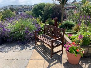 a wooden bench sitting in a garden with flowers at Epchris House in Ilfracombe