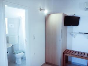 a bathroom with a toilet and a tv on the wall at Mar-Nik Village in Paliochori +32 photos
