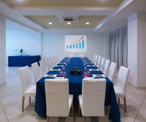 una sala de conferencias con una mesa larga con sillas blancas en Hotel Embassy & Boston, en Milano Marittima