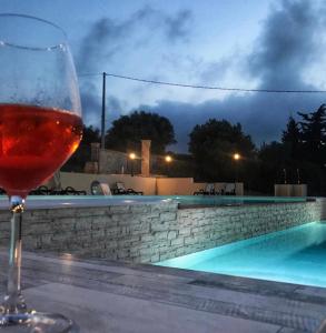 a glass of wine sitting on a table next to a swimming pool at Agriturismo La Casa di Bacco in Agrigento