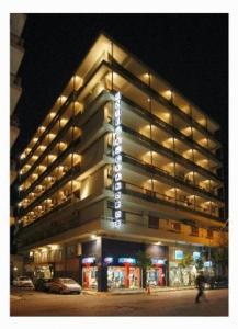 un edificio iluminado con una persona caminando delante de él en Hotel Alexandros, en Volos